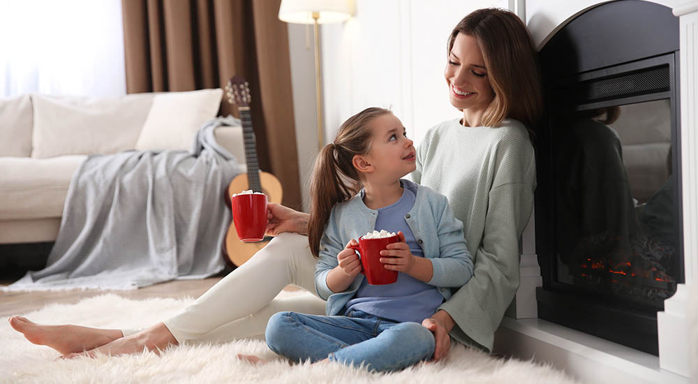 Mother and daughter staying warm by the fire