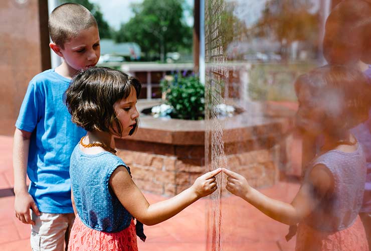 Children looking at names on a veteran's memorial